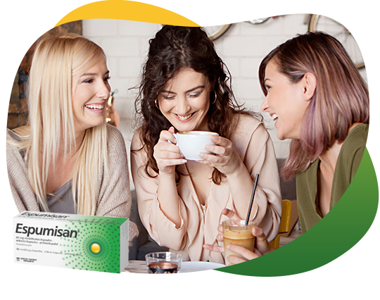 Trīs draudzenes dzer kafiju un labi pavada laiku, runājot par gāzu uzkrāšanos un Espumisan. Priekšplānā ir Espumisan 40 mg kapsulu iepakojuma attēls.