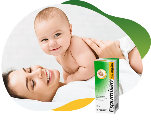 Priekšplānā Espumisan 100 mg/ml emulsijas iepakojums. Fonā priecīgs mazulis smaidot guļ uz mātes un ieinteresēti raugās uz kameru